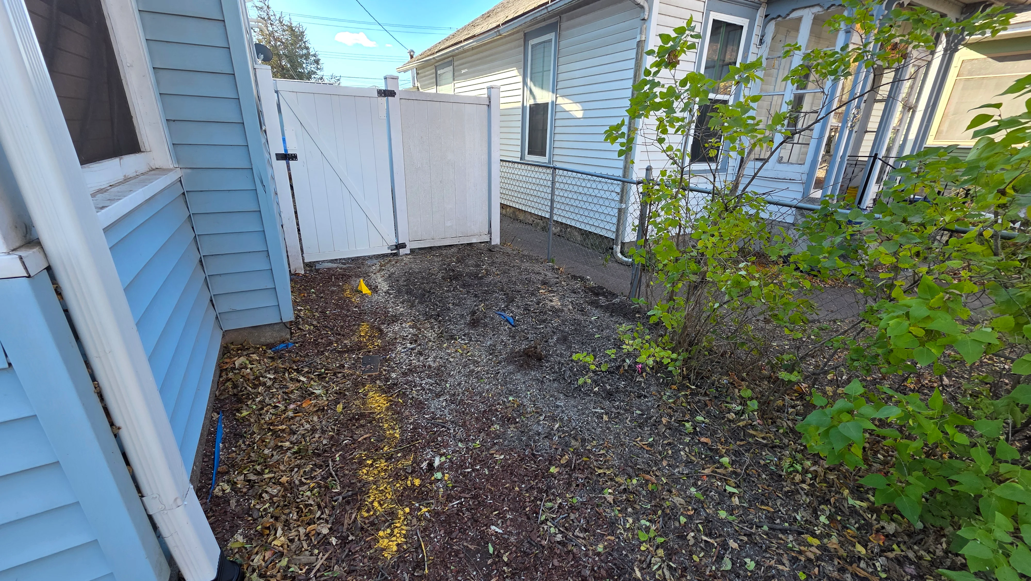 Cleared backyard with mulch, white fence, and adjacent residential structures