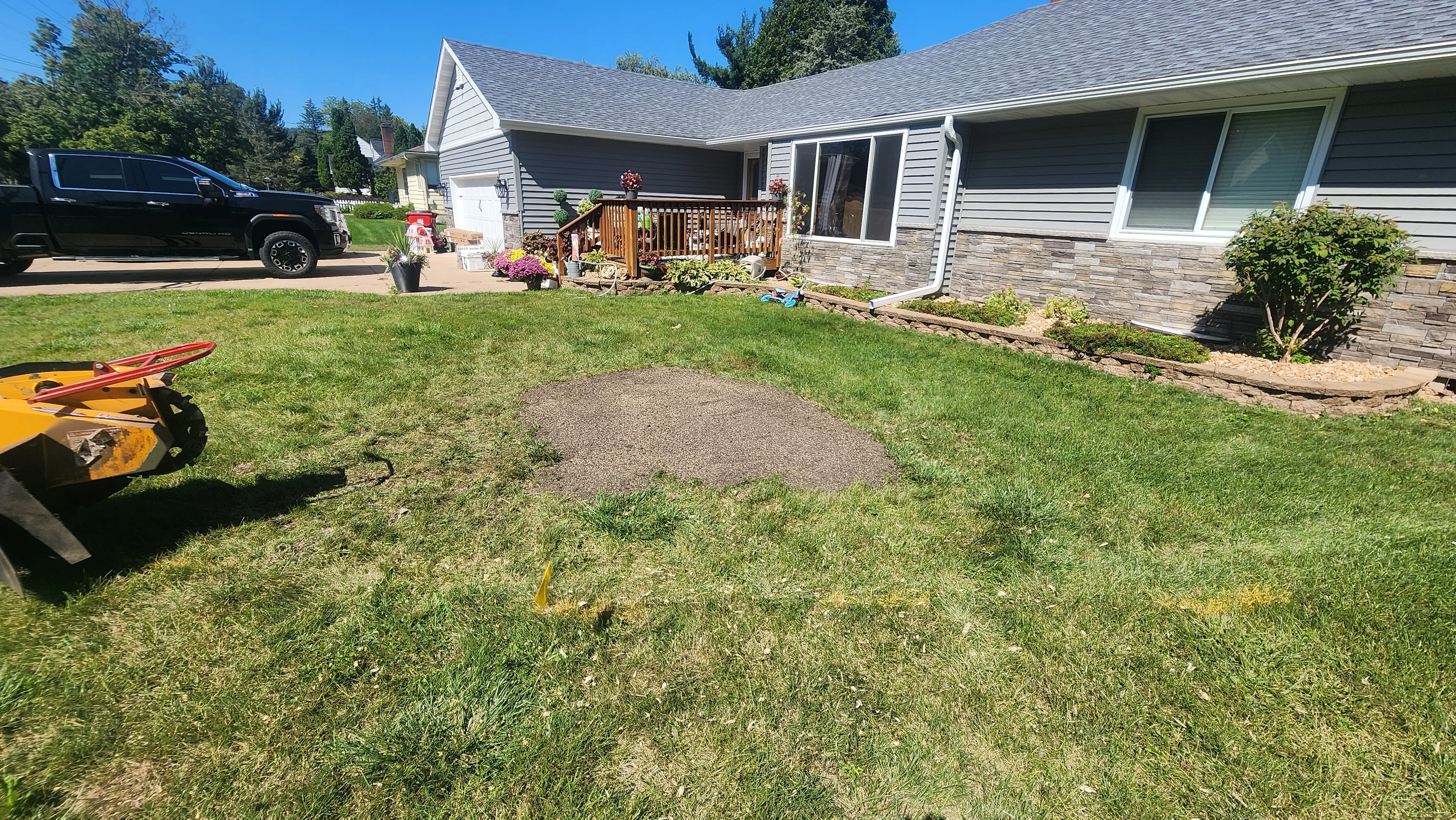 Residential backyard with cleared center area, compacted gravel base, and manicured lawn edges