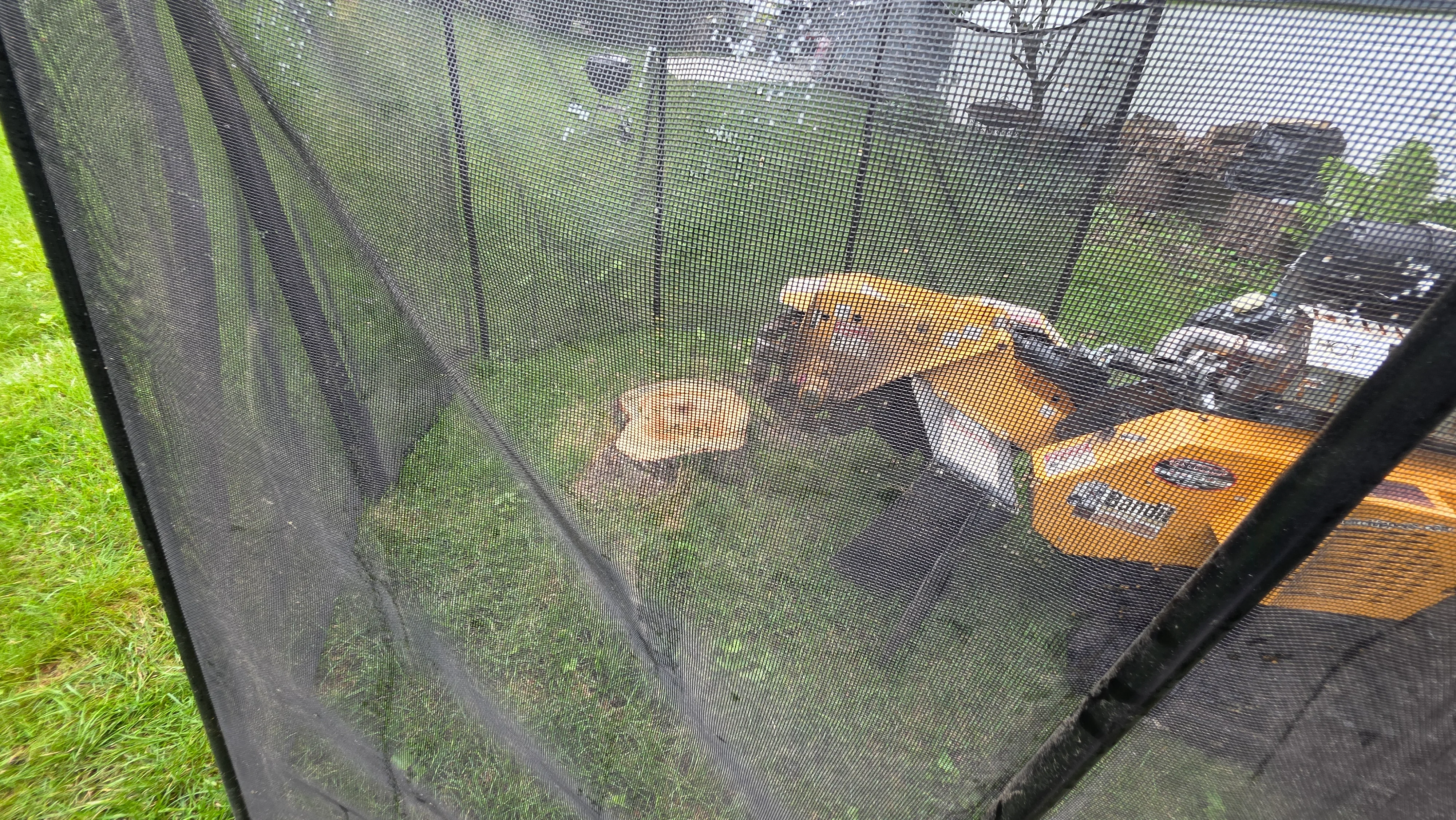 Black mesh safety netting installed on trampoline frame with yellow padding visible