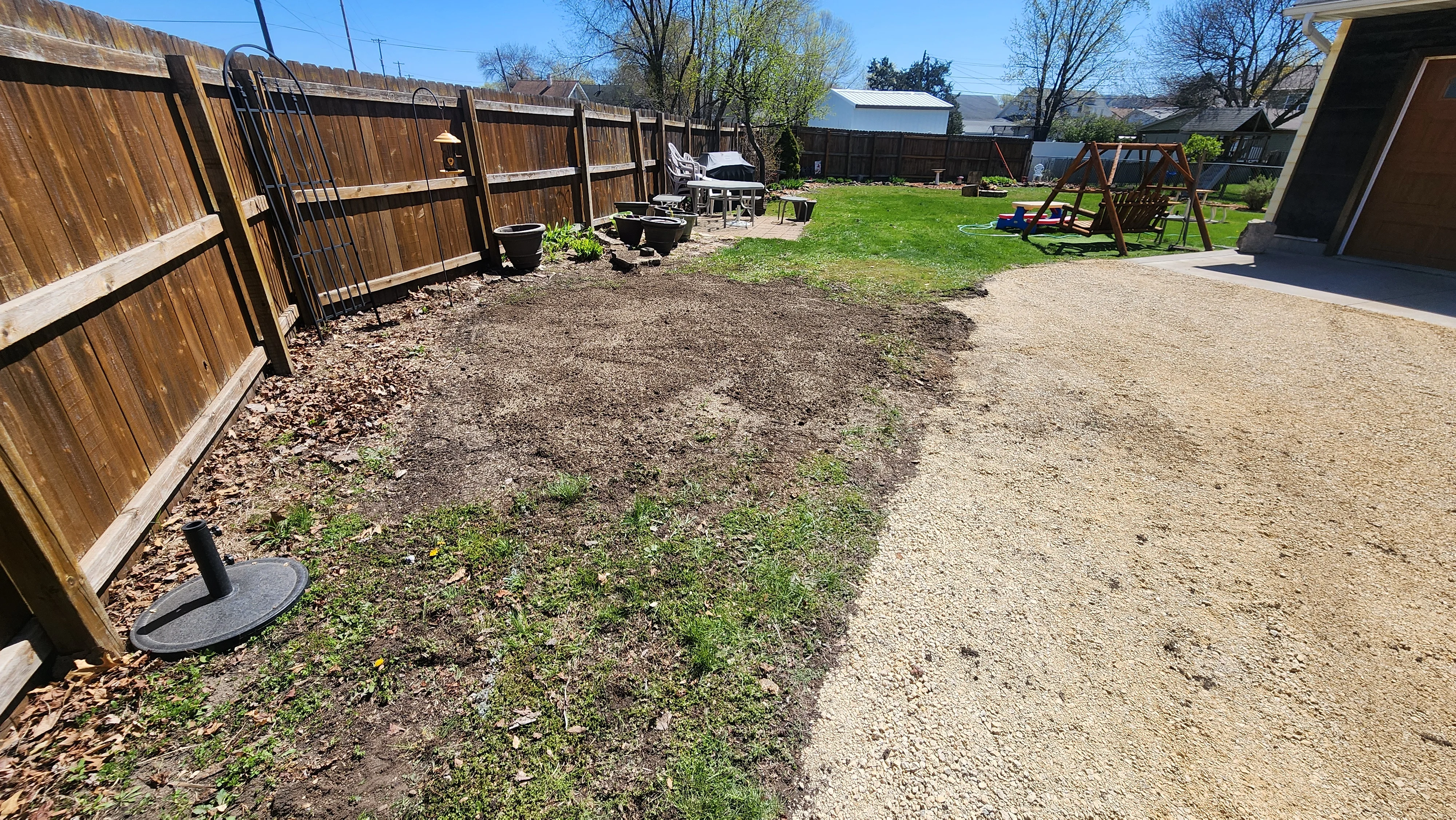 Cleared backyard with gravel base, wooden fence, and prepared ground area
