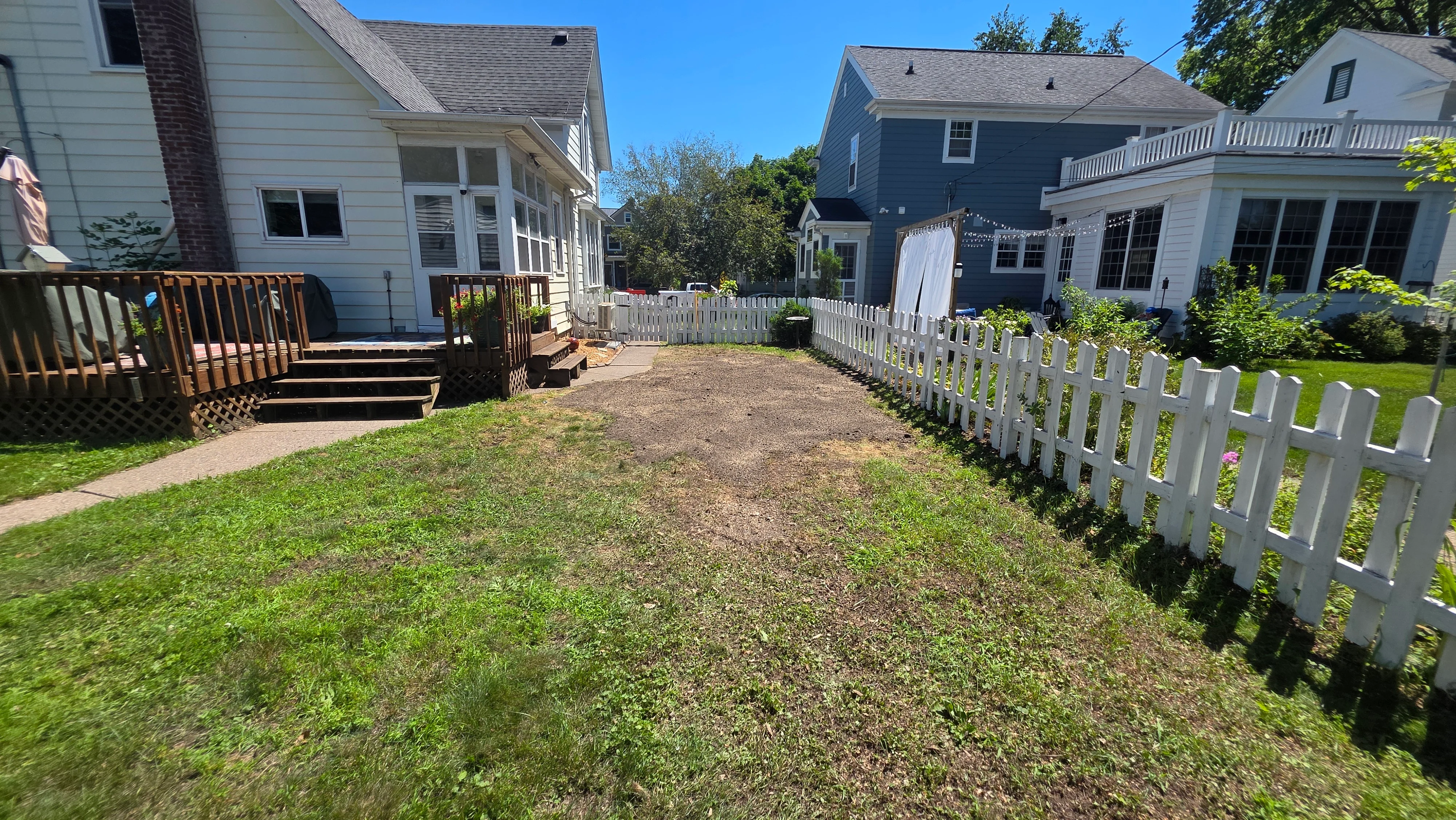 Cleared residential yard with white picket fence, mulch pathways, and manicured lawn borders