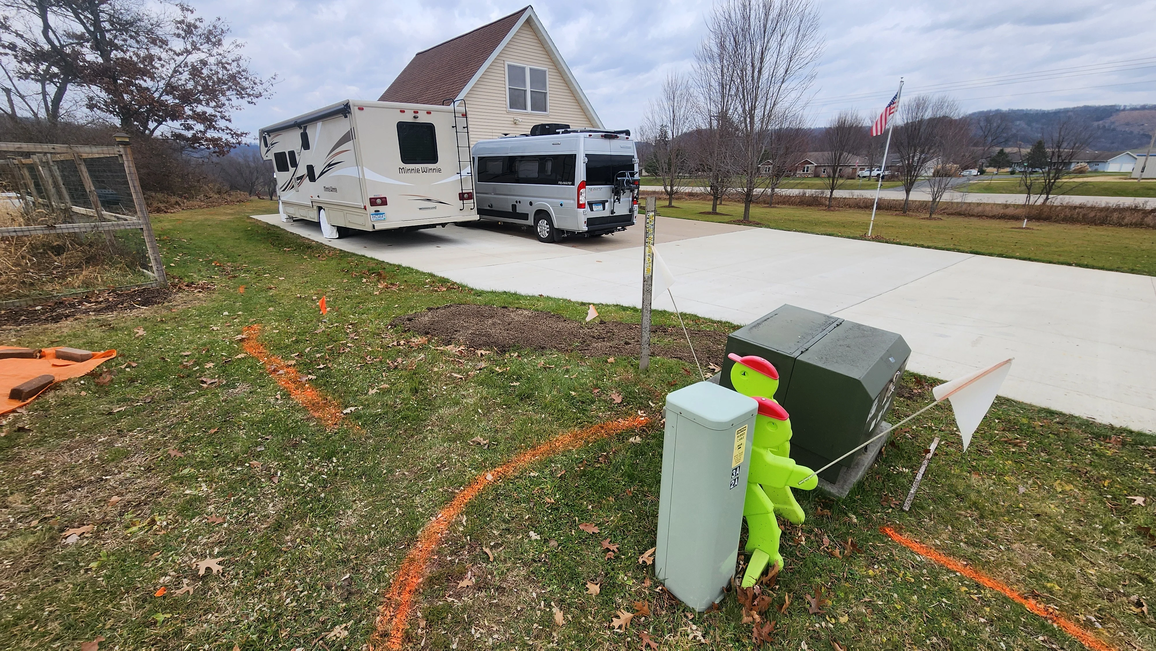 Concrete driveway expansion with RV parking pad, cleared soil, and orange layout markings