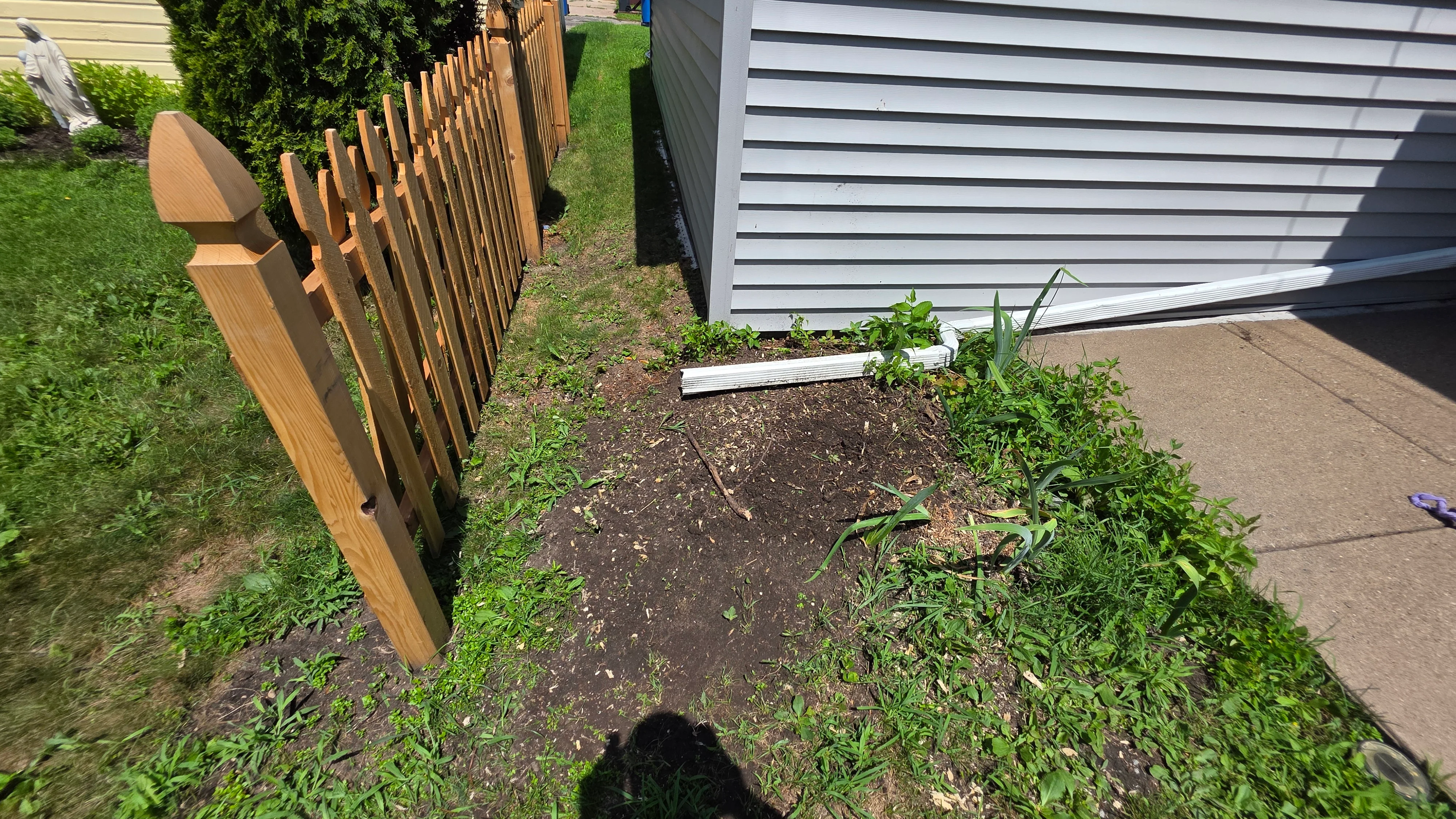 Wooden privacy fence with vertical slats and white aluminum landscape edging along residential property