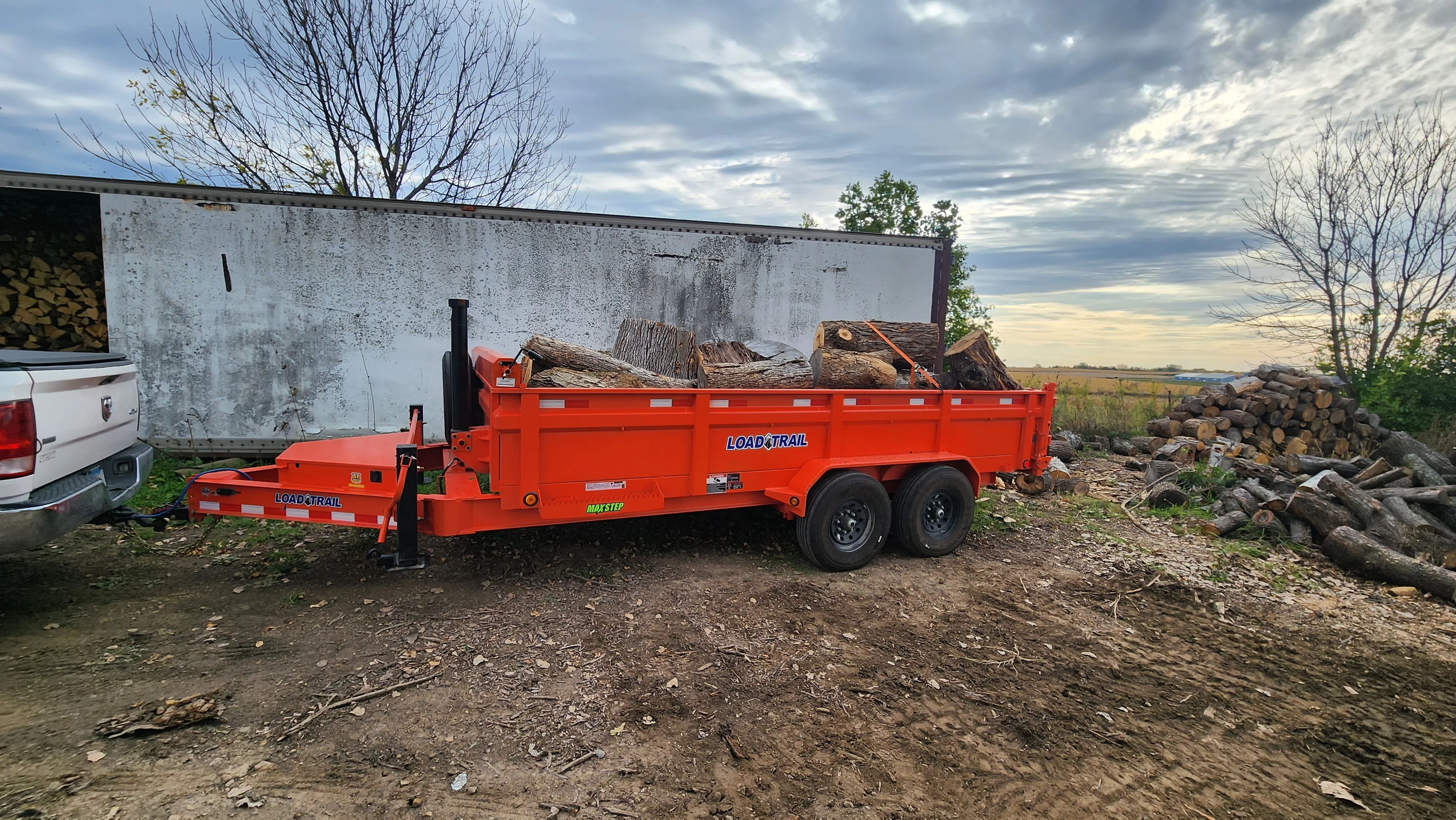 Red dump trailer loaded with logs and wood debris during land clearing operation