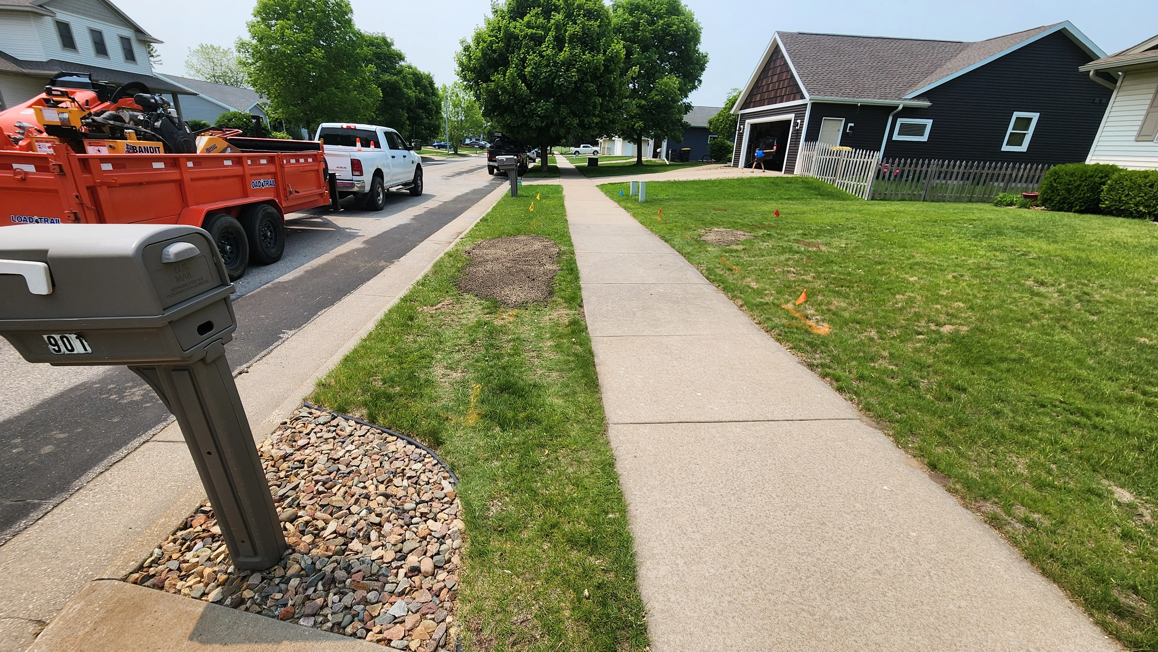 Concrete driveway with river rock borders, edged lawn, and mailbox landscaping