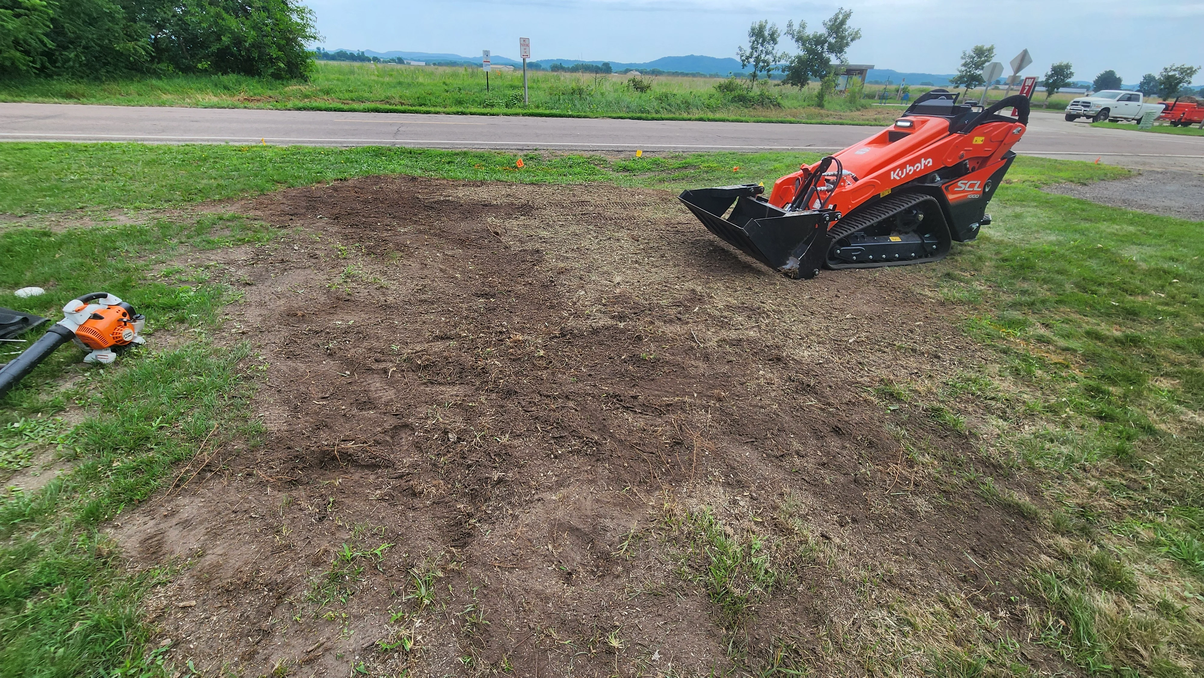 Kubota skid steer with grading bucket on cleared and leveled dirt lot