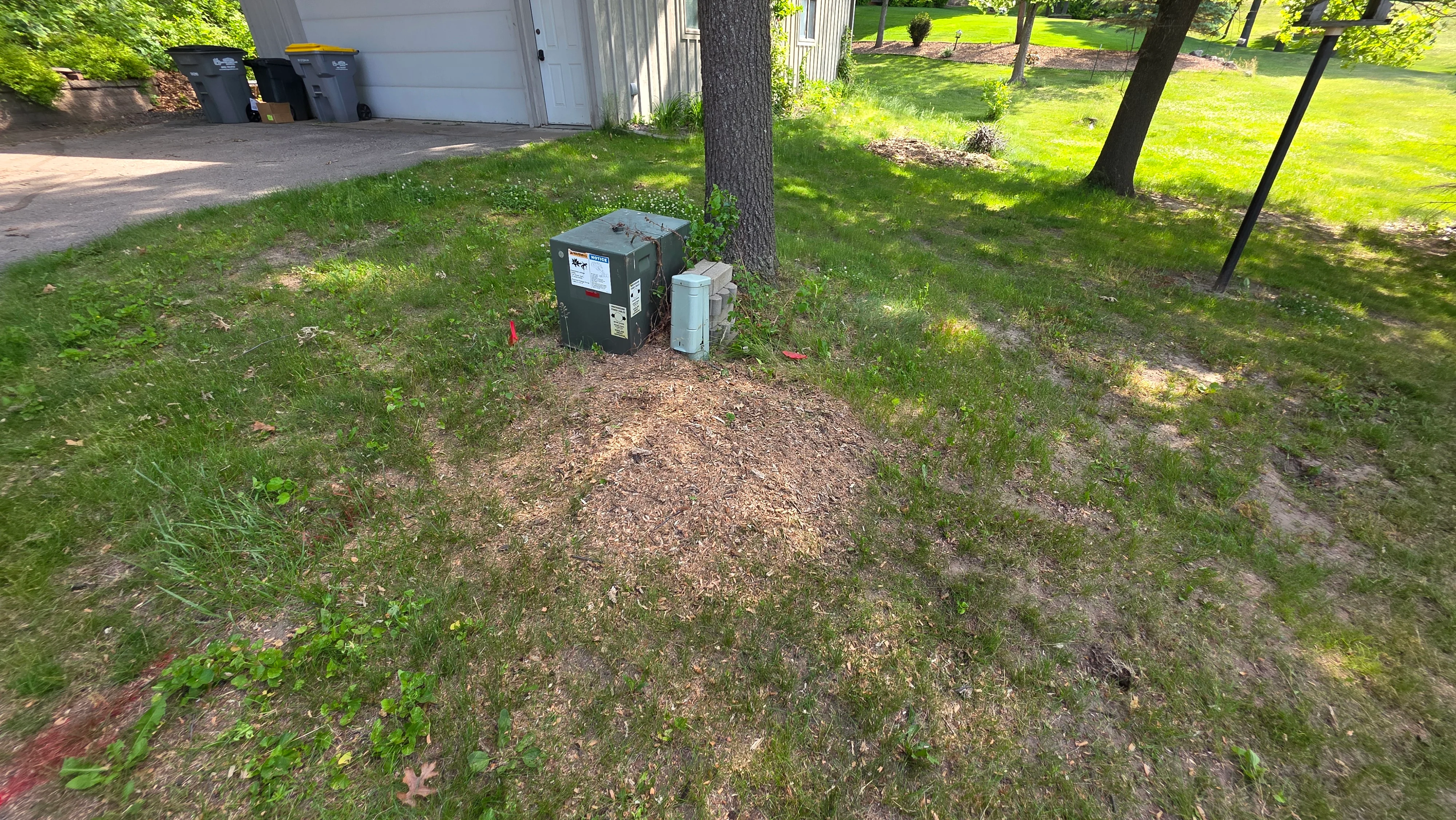 Gravel pad with utility box installation surrounded by cleared lawn and mulch base